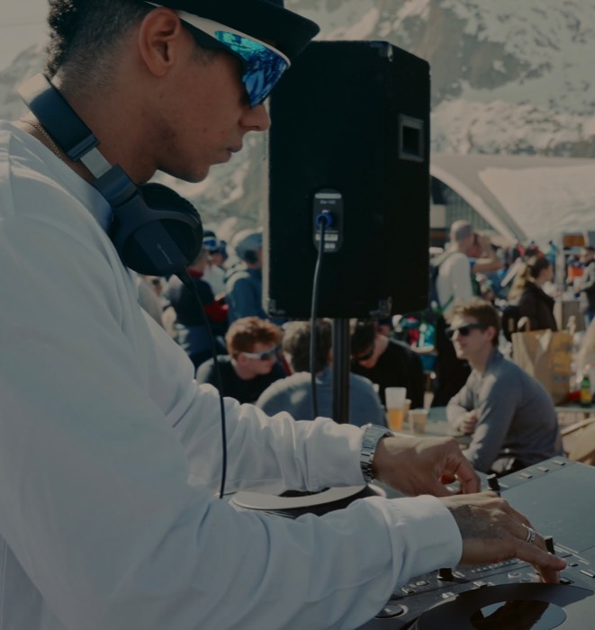 DJ pinchando en altura con público detrás